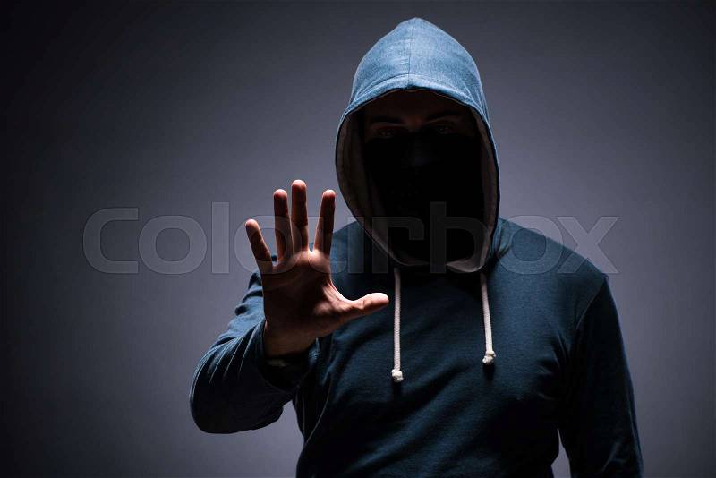 Man wearing hood in dark room, stock photo