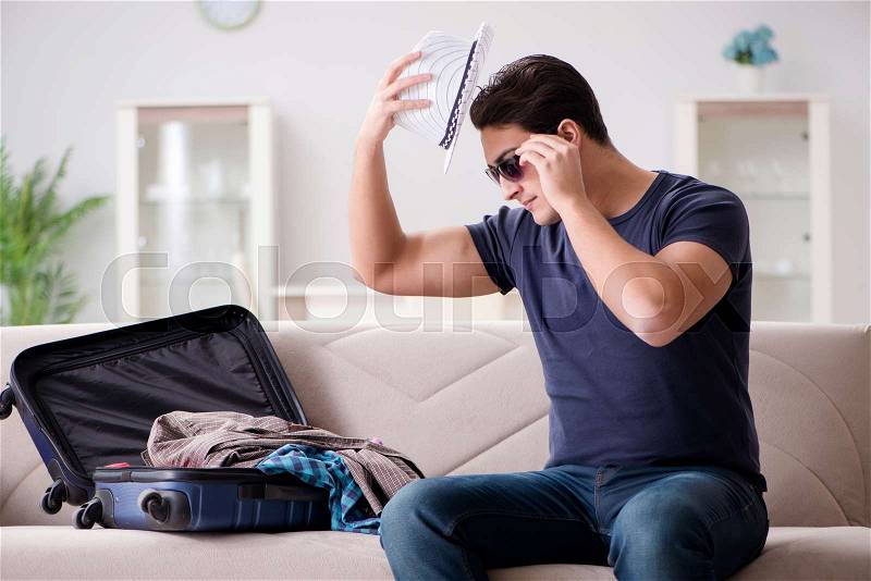 Man going on vacation packing his suitcase, stock photo