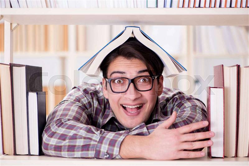 Young student looking for books in college library, stock photo