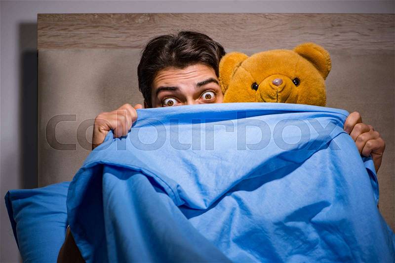 Young man scared in bed, stock photo