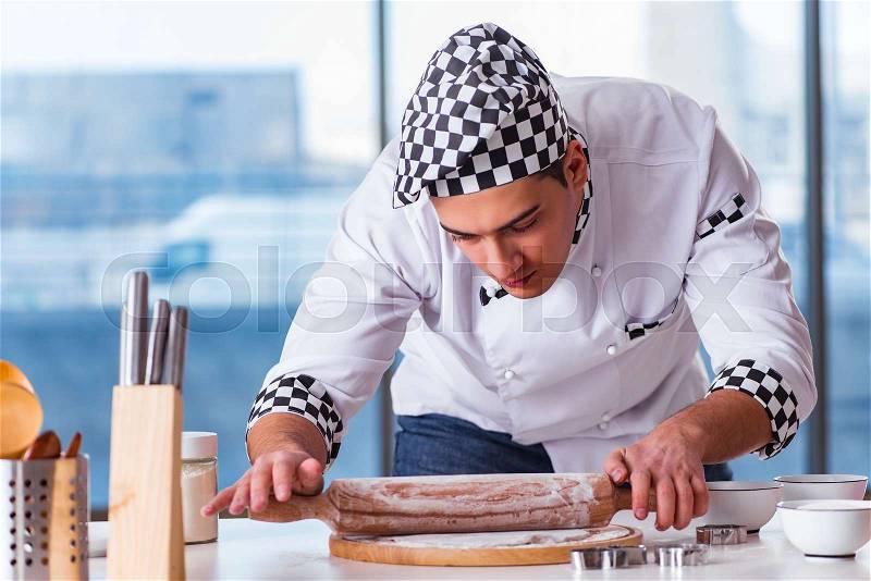 Young man cooking cookies in kitchen, stock photo
