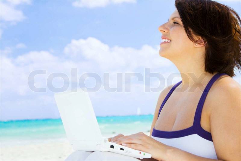 Lovely woman with laptop computer on the beach, stock photo