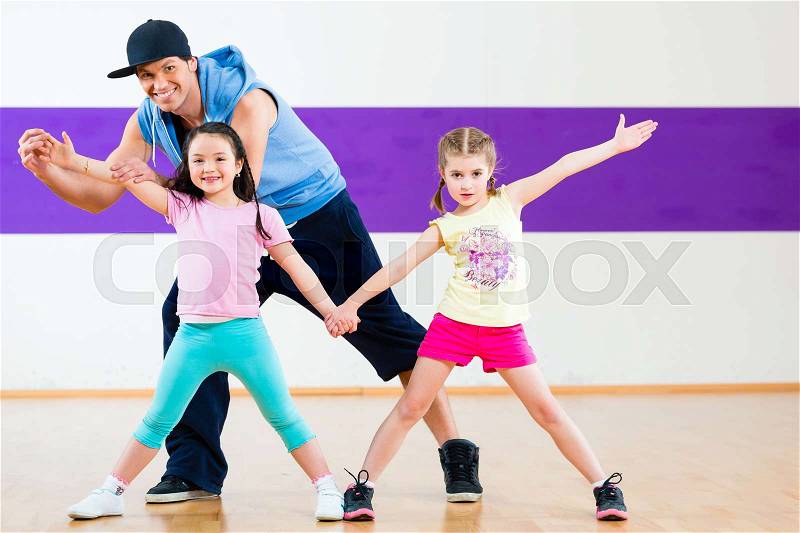 Young dancing teacher training children in modern zumba group choreography , stock photo