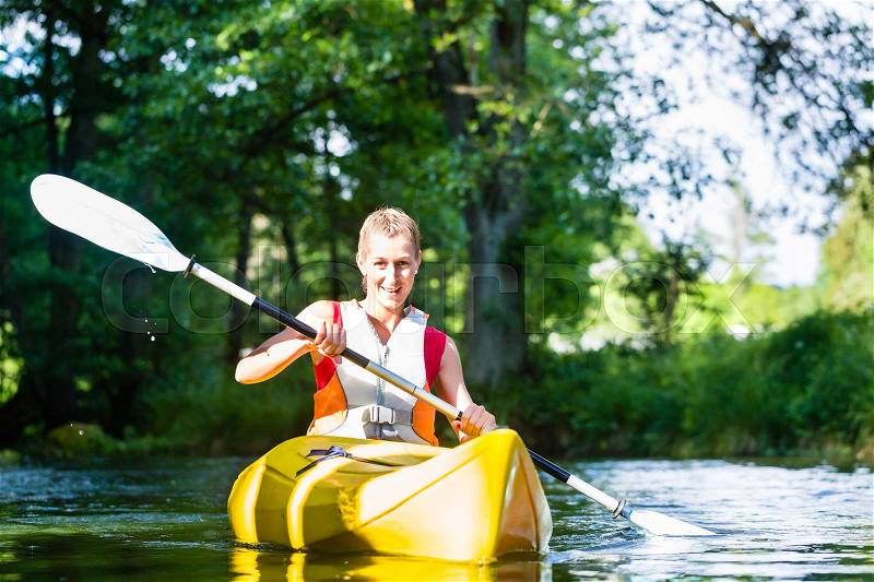 Woman paddling with canoe on forest river, stock photo