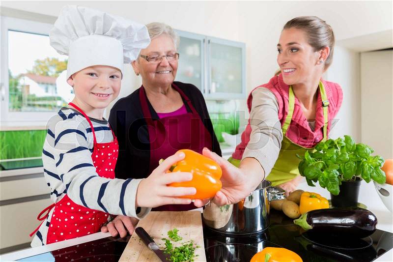 Granny, mum and son talking while cooking in kitchen, stock photo