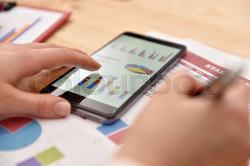 Smart phone with financial data in form of charts and diagrams. Close Up, stock photo