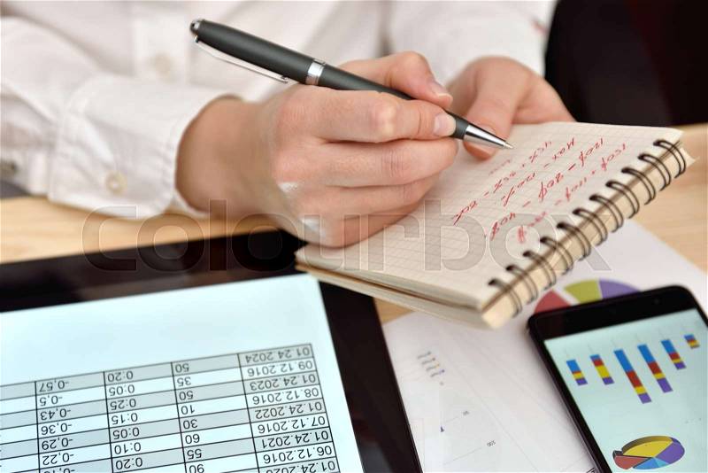 Woman records data in notebook Financial Report. Business analysis and strategy concept, stock photo