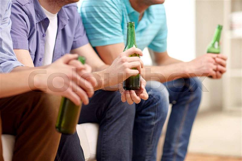 Alcohol and people concept - men with beer bottles sitting on sofa at home, stock photo