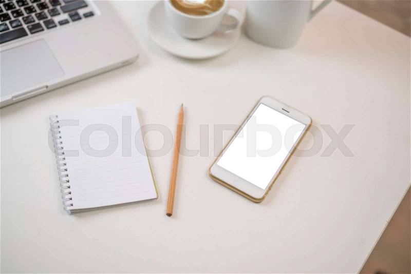 Blank smart phone screen with white blank note book on office desk, stock photo