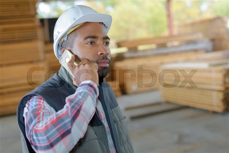 Industrial worker on telephone on a timber yard, stock photo