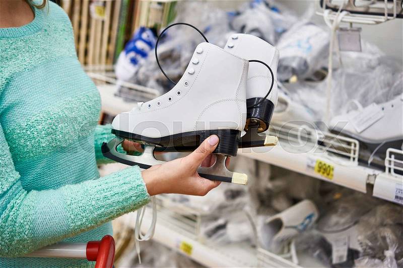 Woman chooses figure skates in the sports shop, stock photo