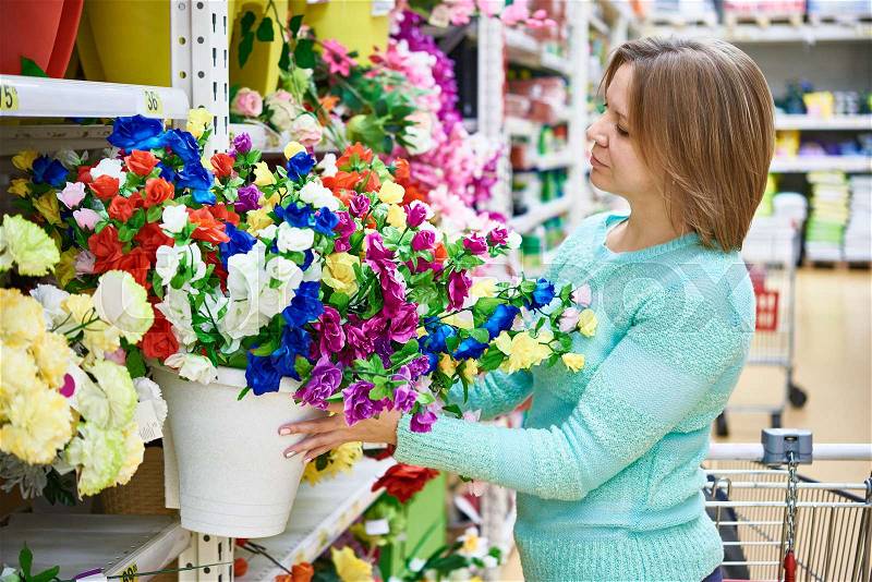 Woman buying flowers in a big supermarket, stock photo