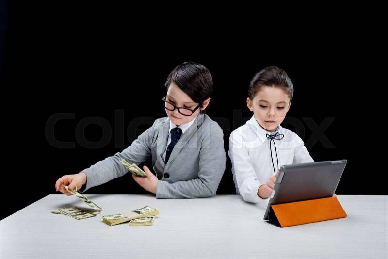Kids playing business people with money and laptop on black, stock photo