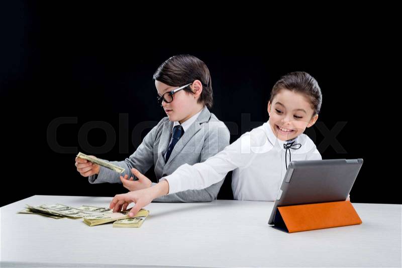 Kids playing business people with money and tablet on black, stock photo