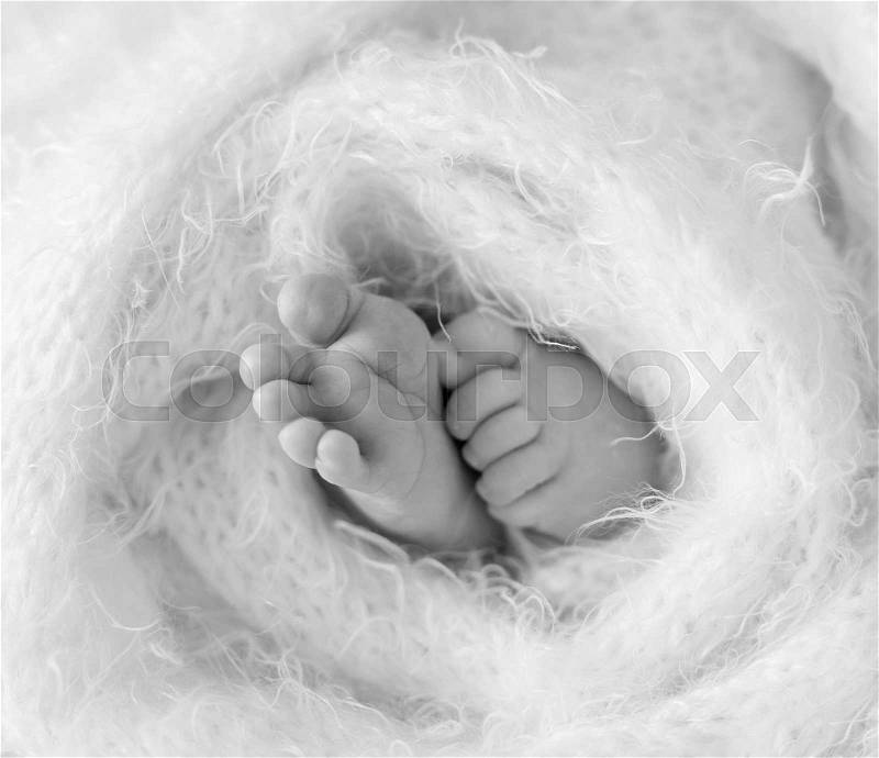 Little feet and toes of an infant sleeping tighly covered with soft warm blanket, stock photo