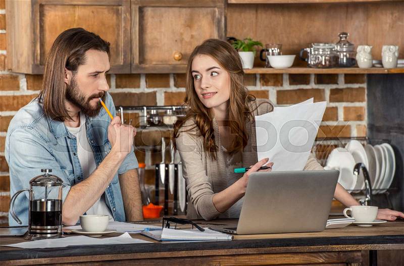 Beautiful young couple working with documents and laptop at home , stock photo