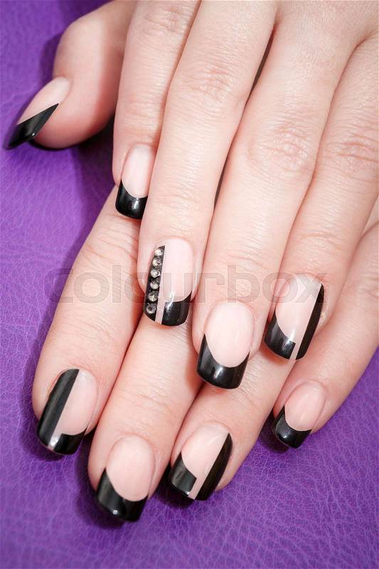 Female hands with black manicure on the violet background, stock photo