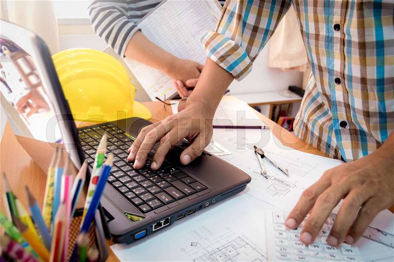 Two colleagues discussing data working with construction plan in office, stock photo