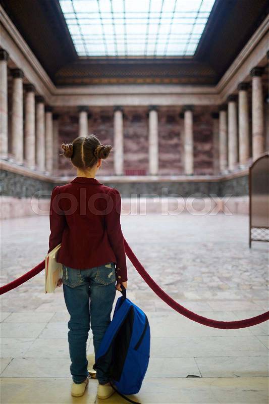 Girl with school-bag looking at ancient colonnade in museum, stock photo