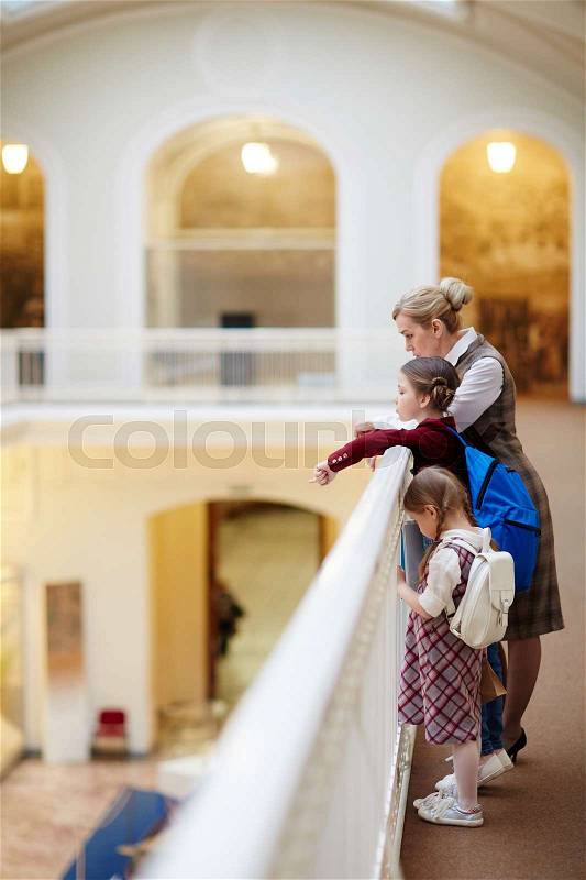Schoolgirls and their teacher spending leisure in museum, stock photo