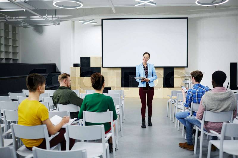 Young lecturer consulting her students attending course of study, stock photo