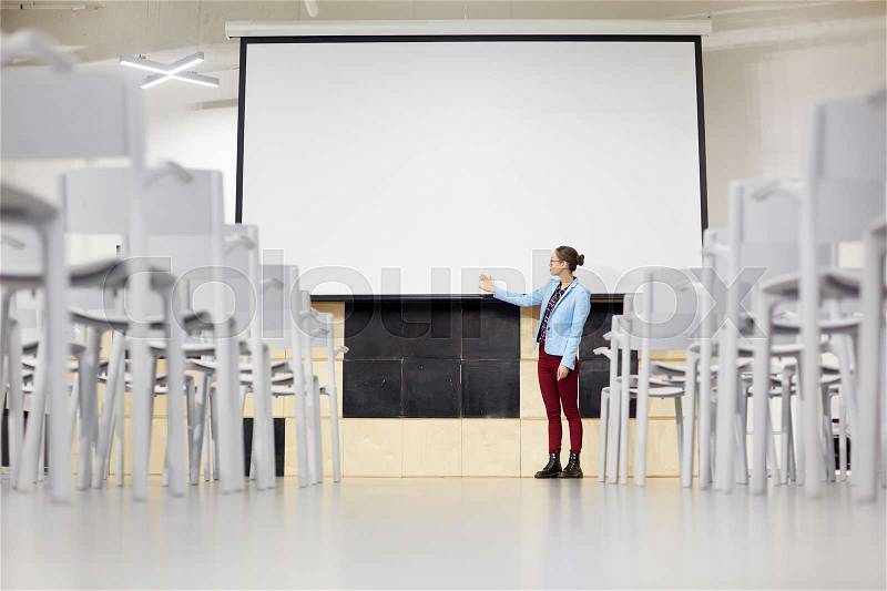 Young student pointing at blank whiteboard, stock photo
