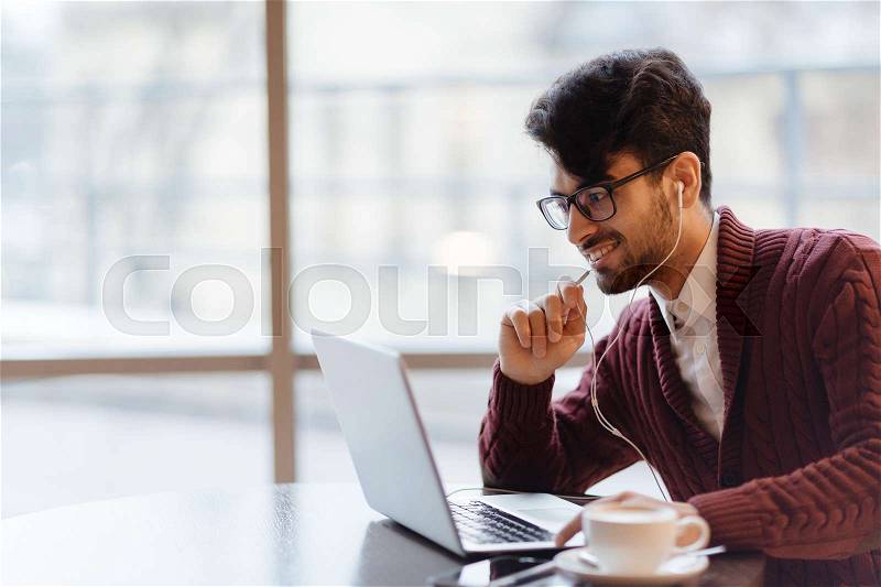 Businessman with earphones watching video conference or seminar online, stock photo
