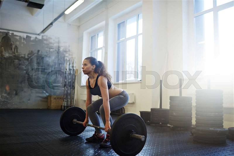 Strong young woman practicing weightlifting, stock photo