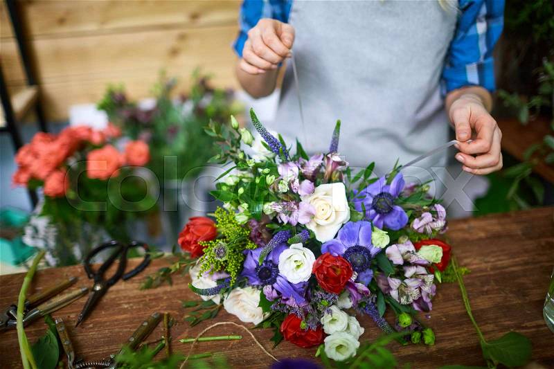 Fresh floral bouquet being tied by florist, stock photo