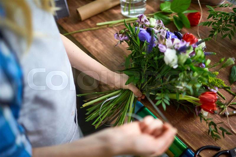Florist tying floral bouquet with ribbon, stock photo