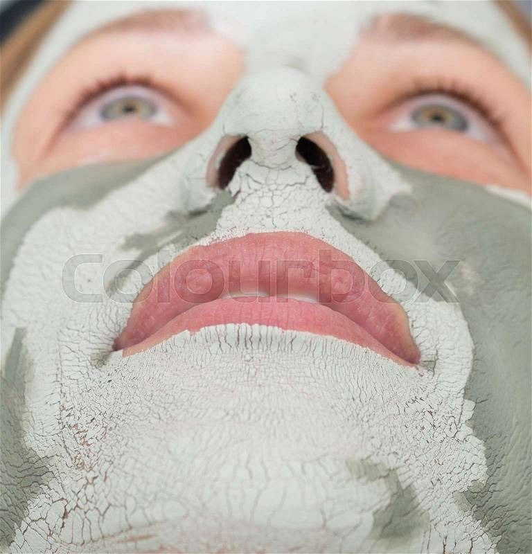 Young beautiful woman with clay mask on her face, stock photo