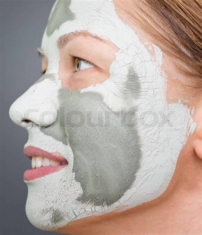 Young beautiful woman with clay mask on her face, stock photo
