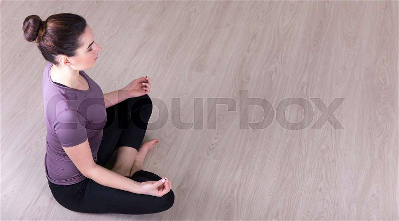 Top view of young slim woman sitting in yoga pose on the floor, stock photo
