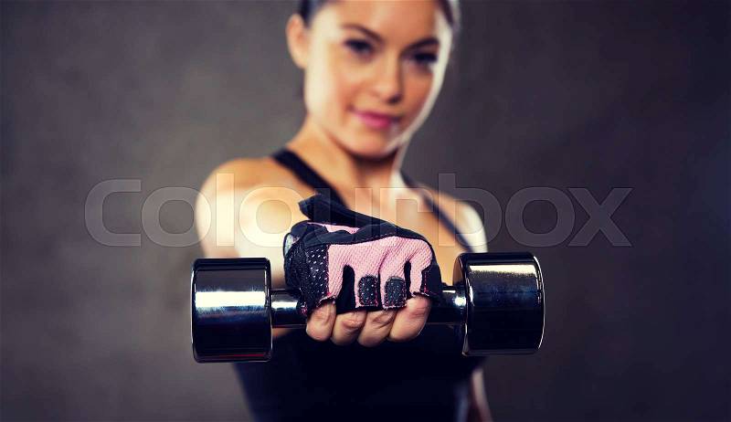 Sport, fitness, bodybuilding, weightlifting and people concept - close up of woman holding dumbbell in gym, stock photo