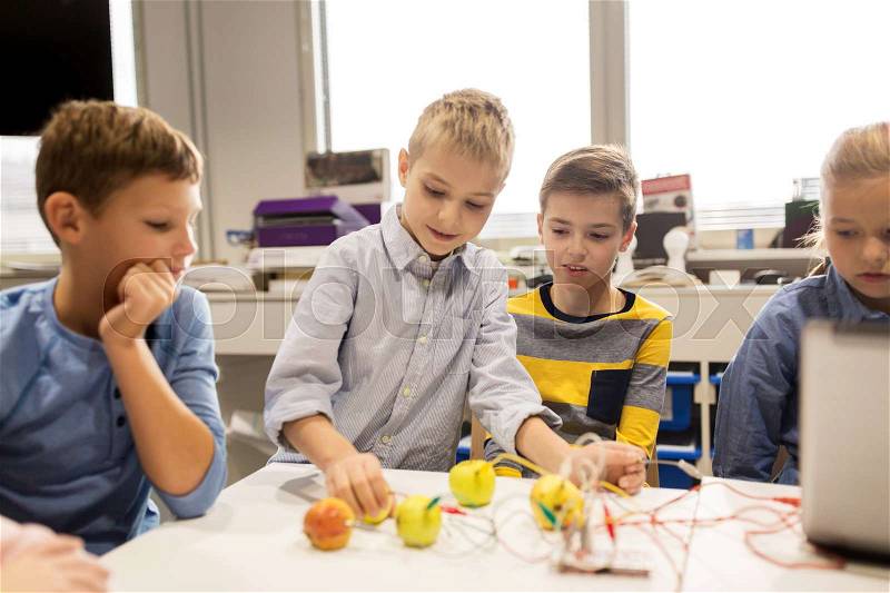 Education, children, technology, science and people concept - group of happy kids with laptop computer playing and invention kit at robotics school lesson, stock photo