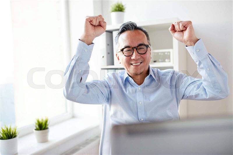 Business, people, success and technology concept - happy businessman with laptop celebrating victory at office, stock photo