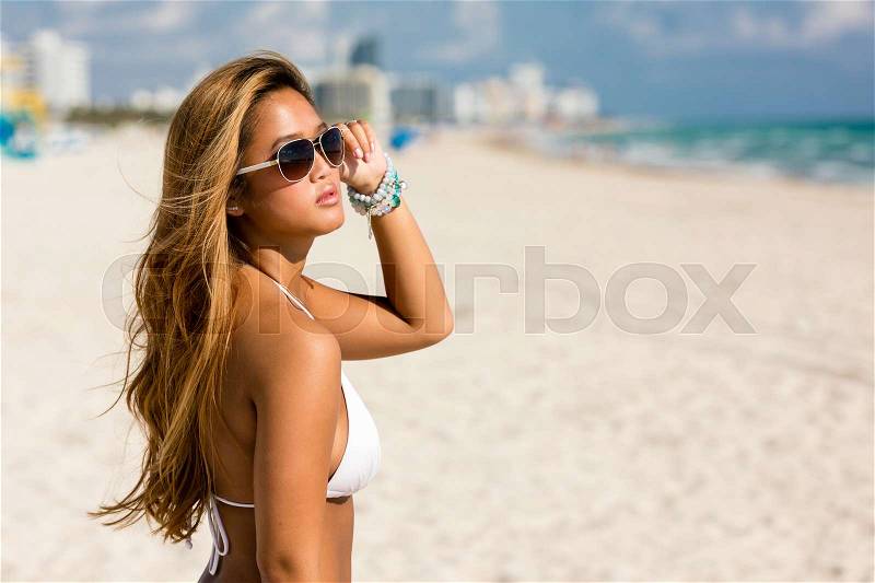 Portrait of pretty beautiful woman in white bikini posing in sunshine on vacation, stock photo