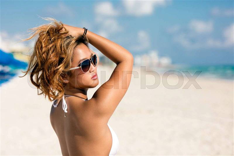 Portrait of pretty beautiful woman in white bikini posing in sunshine on vacation, stock photo