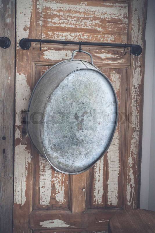 Old stylish iron tub hanging on a wooden wall with grunge paint peeling of the old planks, stock photo