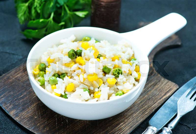 Rice with vegetables in bowl and on a table, stock photo