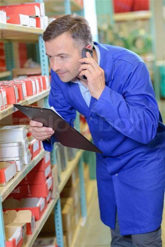 Man in stores on telephone holding clipboard, stock photo