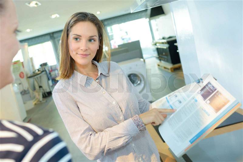 Shopper chosing oven from catalog in electronic appliance shop, stock photo
