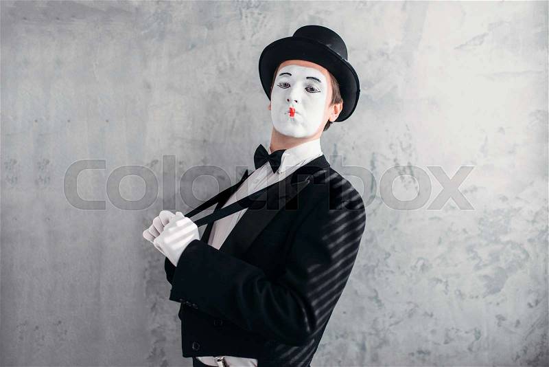 Mime male artist with white makeup mask. Comedy actor in suit, gloves and hat. Mimic person. April fools day concept, stock photo