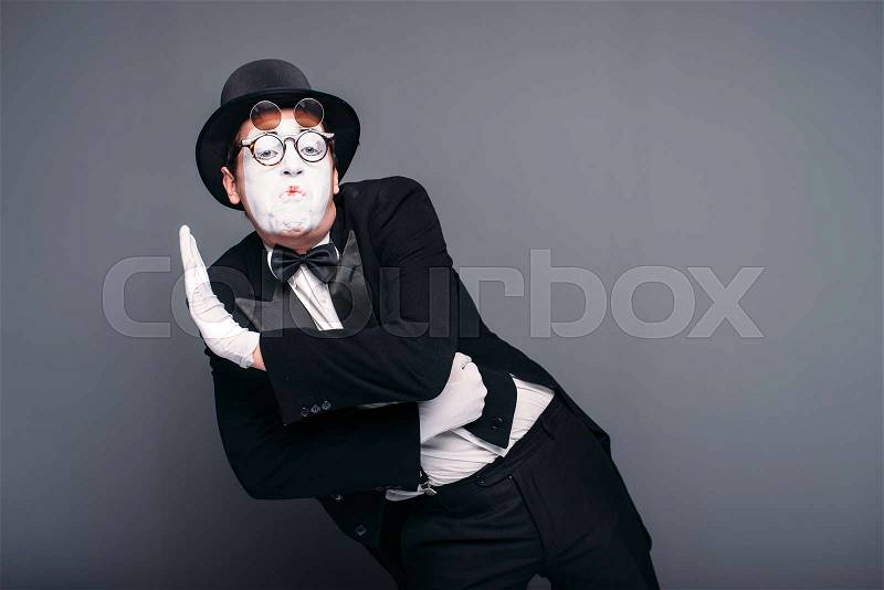Male pantomime actor fun performing. Mime in suit, gloves, glasses, make-up mask and hat. April fools day concept, stock photo