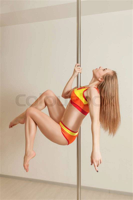 Young attractive pole dance woman exercising in studio, stock photo