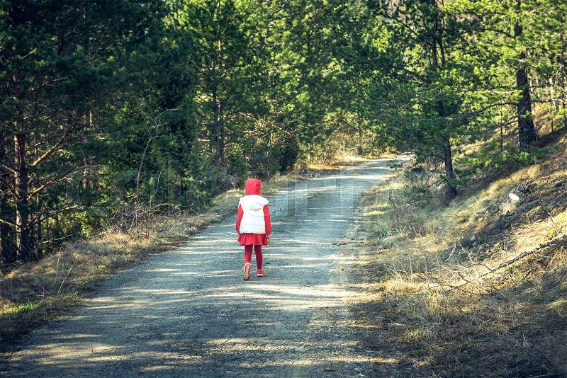 Little girl in red walking in the woods, stock photo