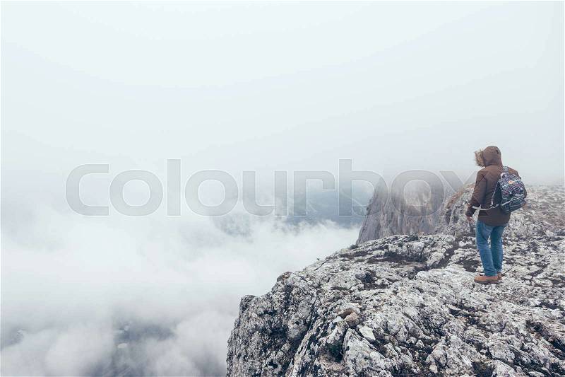 Man with backpack trekking in mountains. Cold weather, fog and clouds. Winter hiking, stock photo