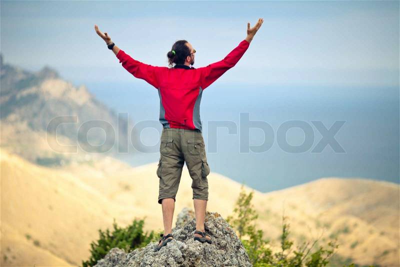 Man on top of mountain holding arms up, stock photo
