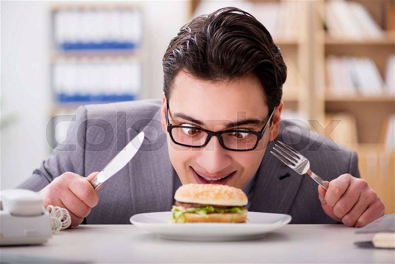 Hungry funny businessman eating junk food sandwich, stock photo