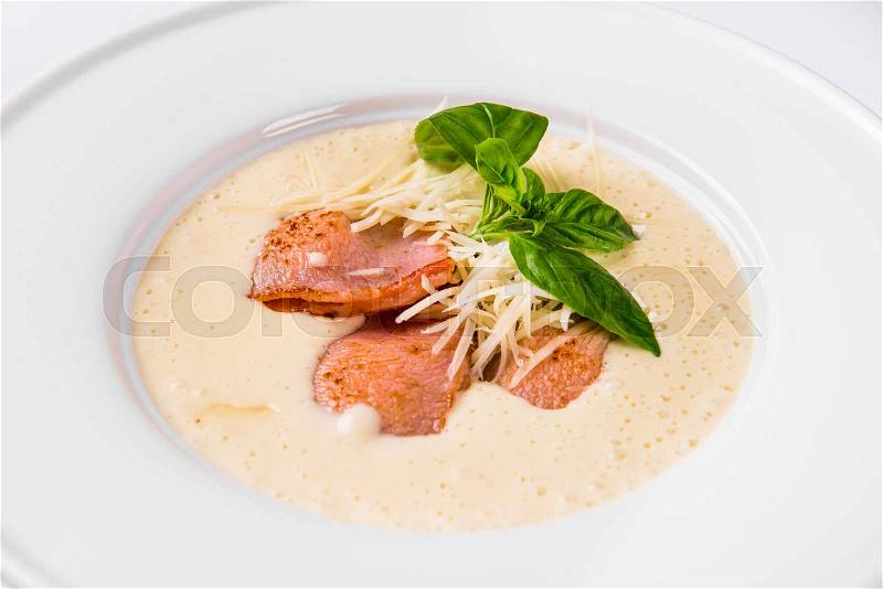 Cream soup with basil, meat steak and cheese on plate. Close-up, white background, stock photo